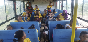 várias crianças dentro de um ônibus junto do fotógrafo voluntário do instituto omunga, todos sorrindo para a foto